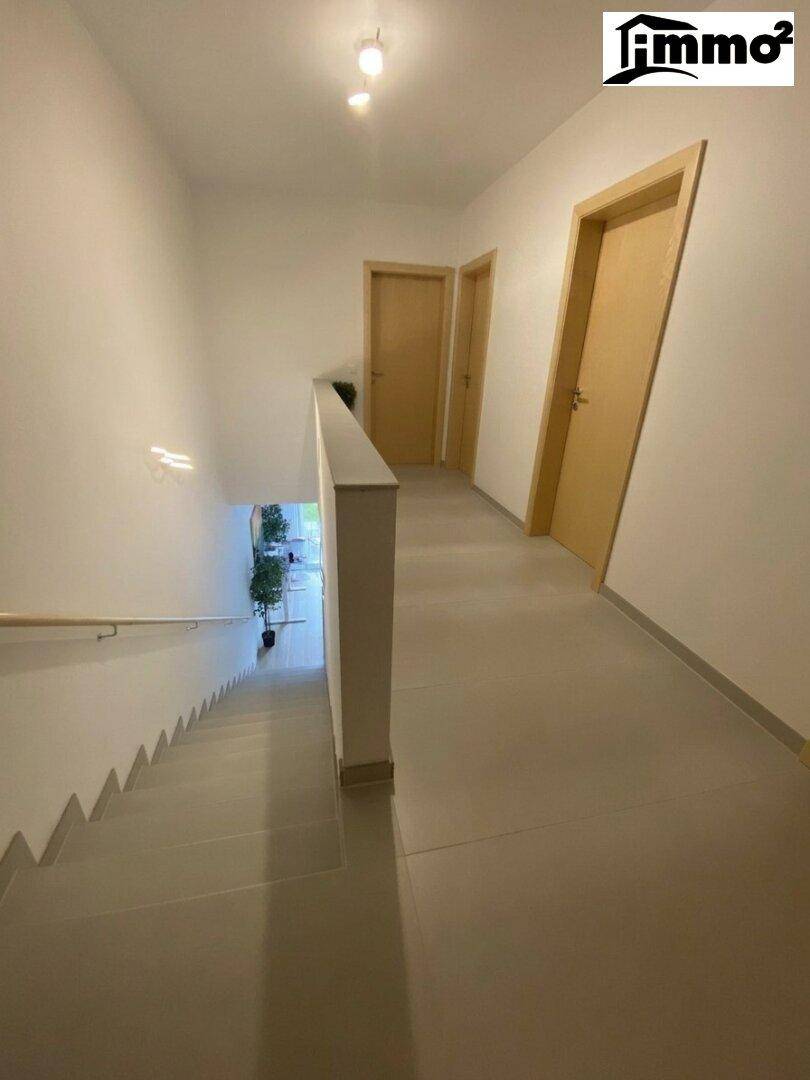 Heller Flur im Obergeschoss mit Türen zu den Zimmern und Blick auf die Treppe.