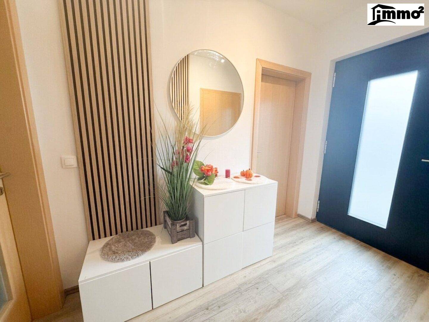Heller Eingangsbereich mit modernem Spiegel, Garderobe und Holzakzenten an der Wand.