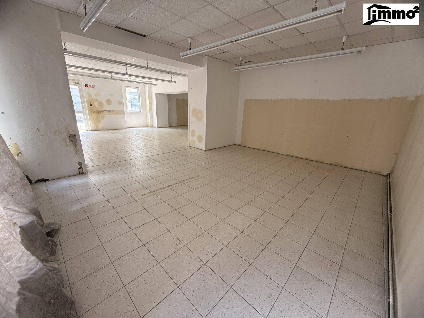 Weiterer Blick in den weitläufigen Raum mit Fliesenboden und Renovierungsbedarf.