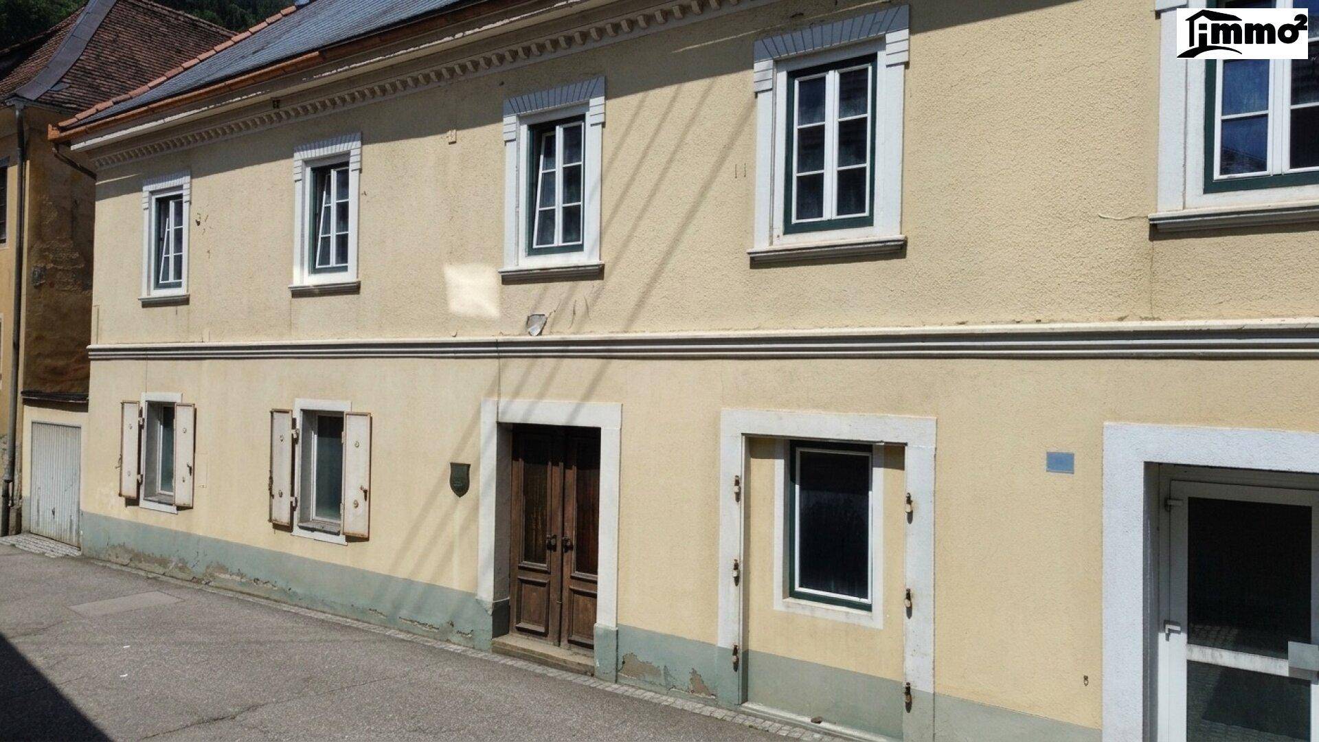 Detailansicht der gelben Fassade mit Holztür und traditionellen Fenstern.