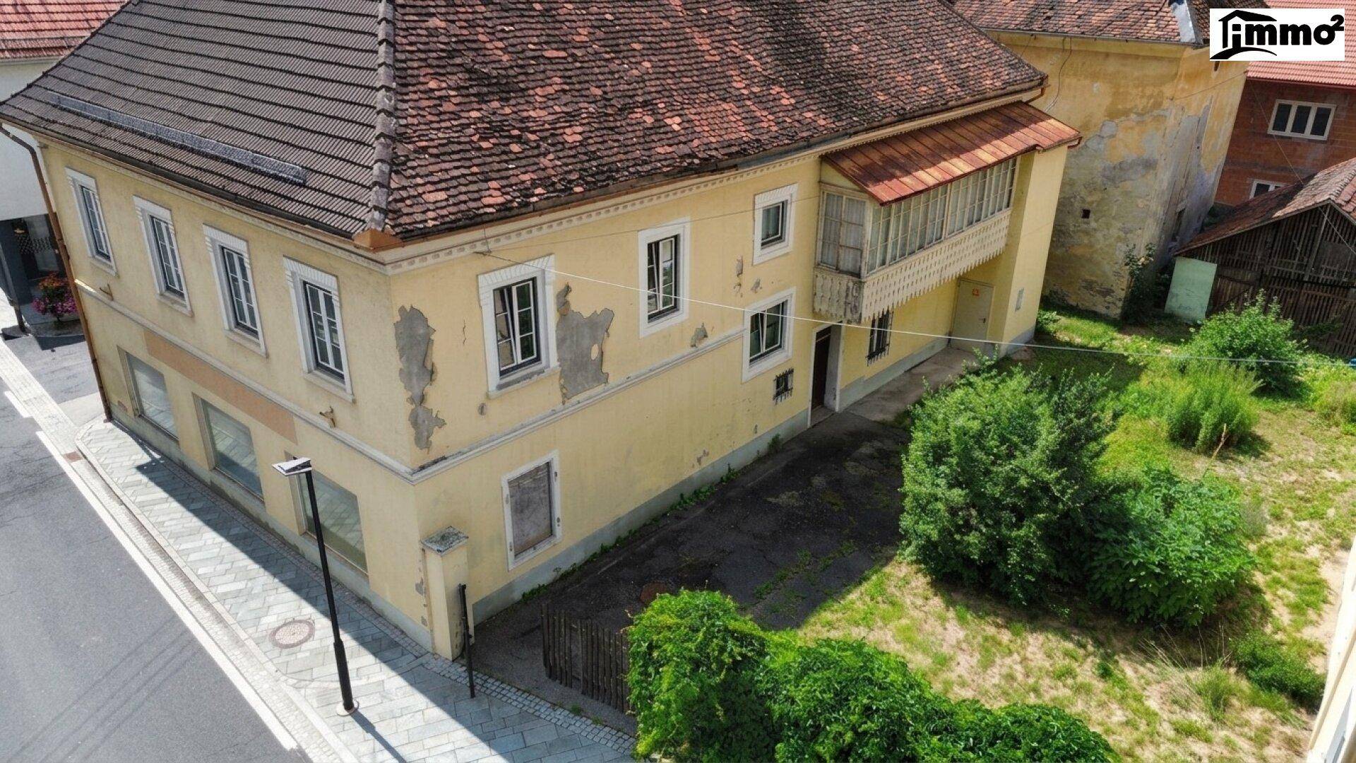 Seitenansicht des Gebäudes mit Gartenfläche und einem überdachten Balkon.