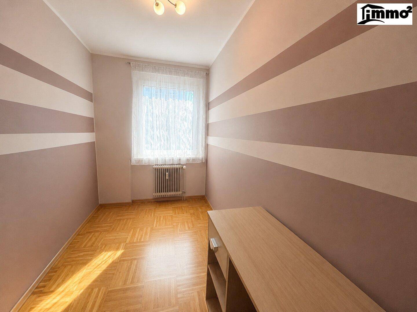 Schlafzimmer mit Parkettboden, gestreiften Wänden und einem Fenster für natürliches Licht.