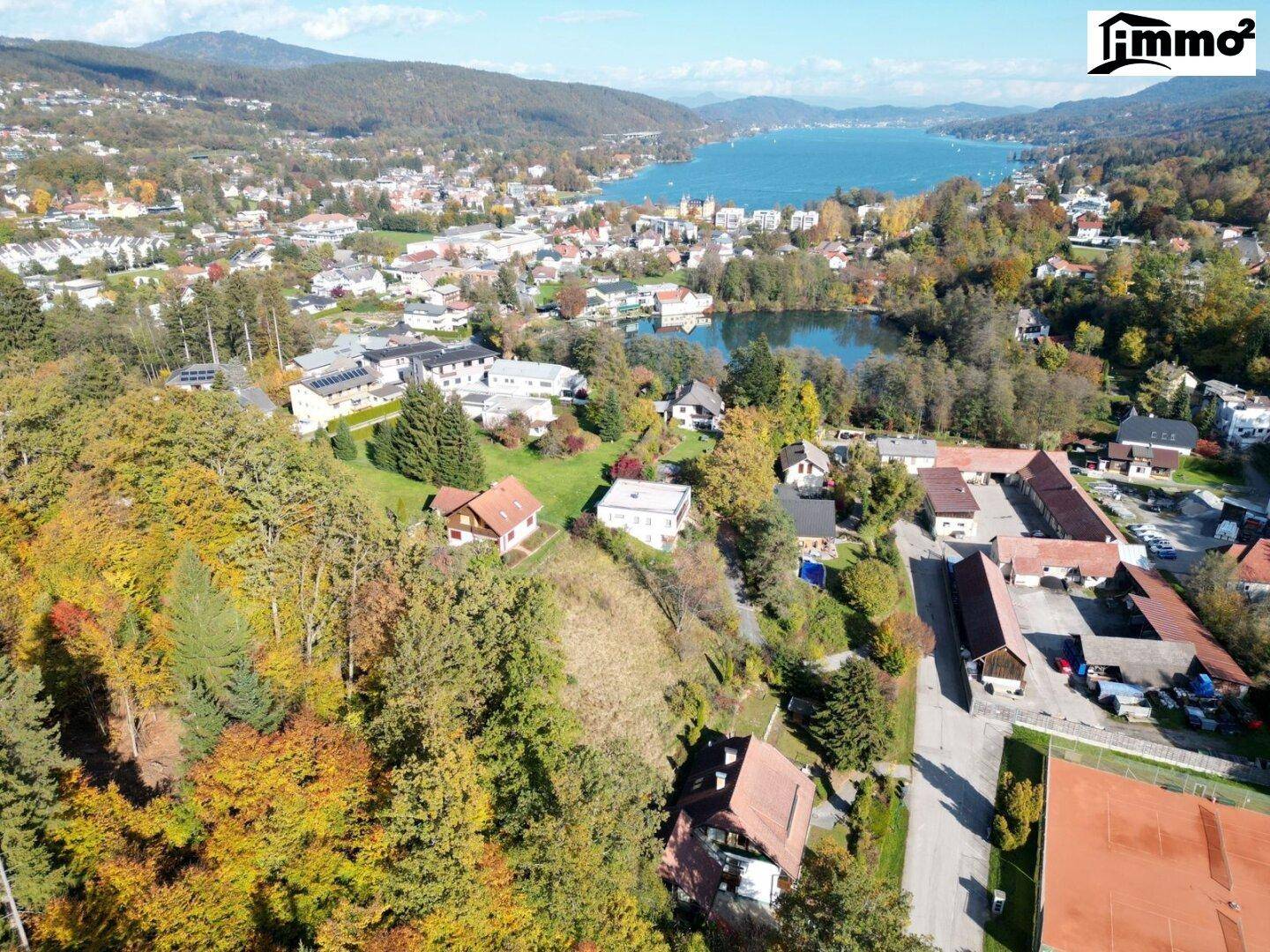 Weitläufige Luftaufnahme der Wohngegend mit See, Wald und umliegenden Häusern.