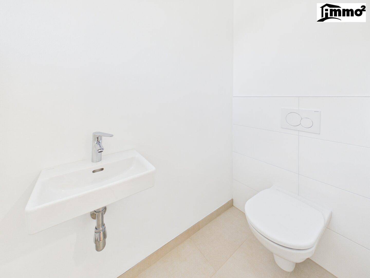 Modernes Gäste-WC mit wandhängender Toilette und kleinem Eckwaschbecken in minimalistischem Design.