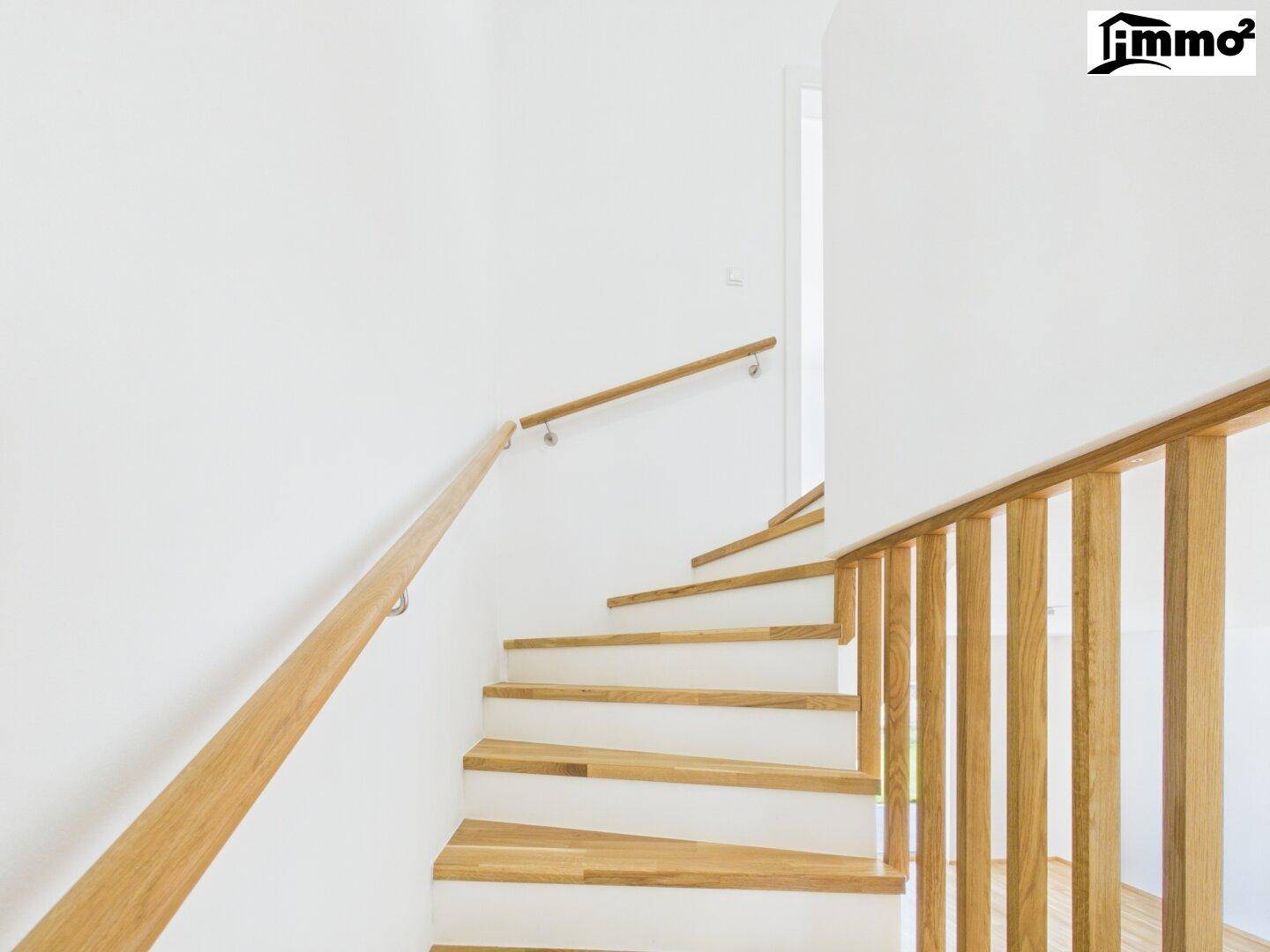 Moderne Holztreppe mit elegantem Geländer und Handlauf, die die Etagen verbindet.