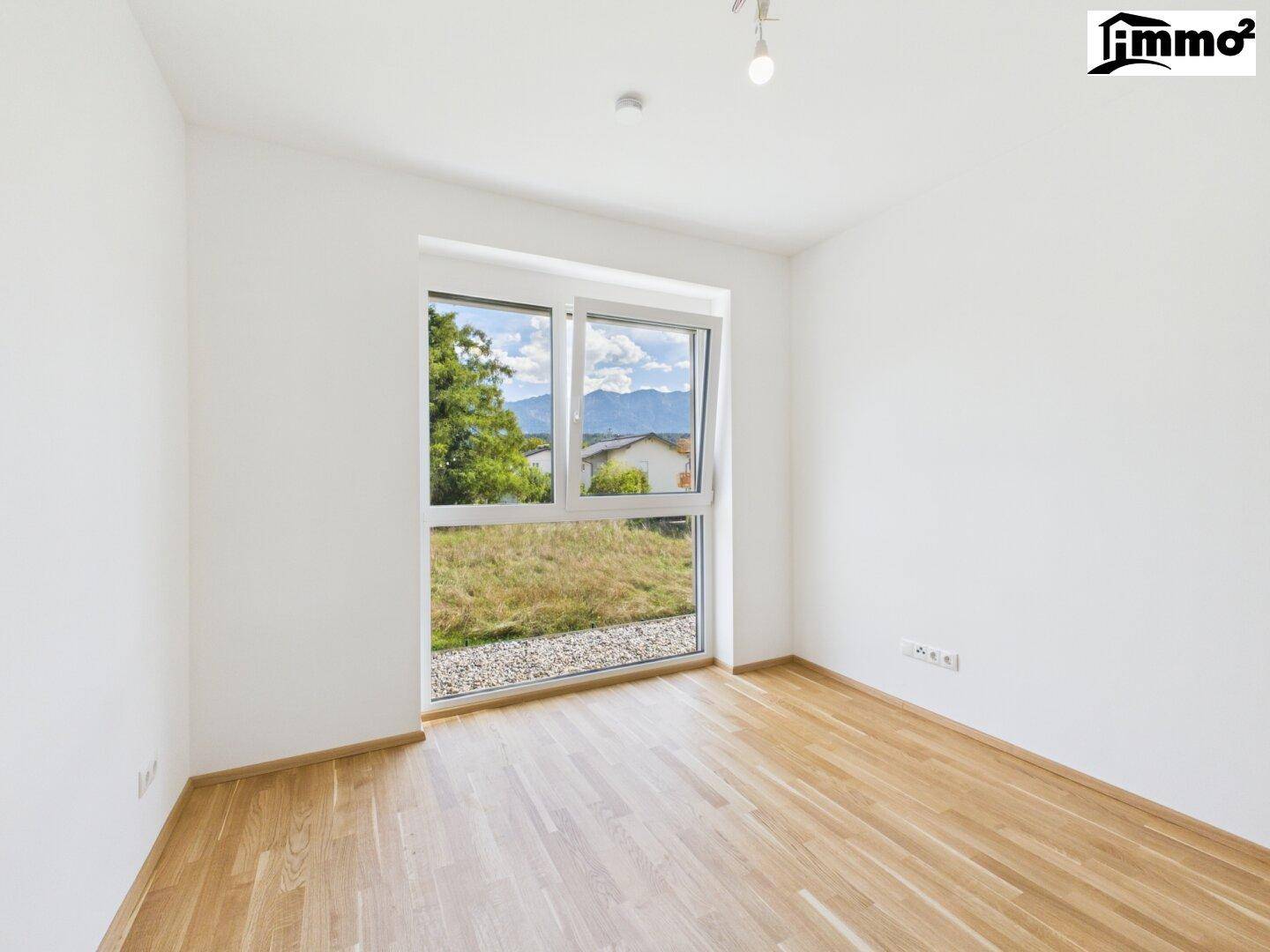 Helles Zimmer mit Holzboden und großem Fenster, das einen schönen Bergblick bietet.