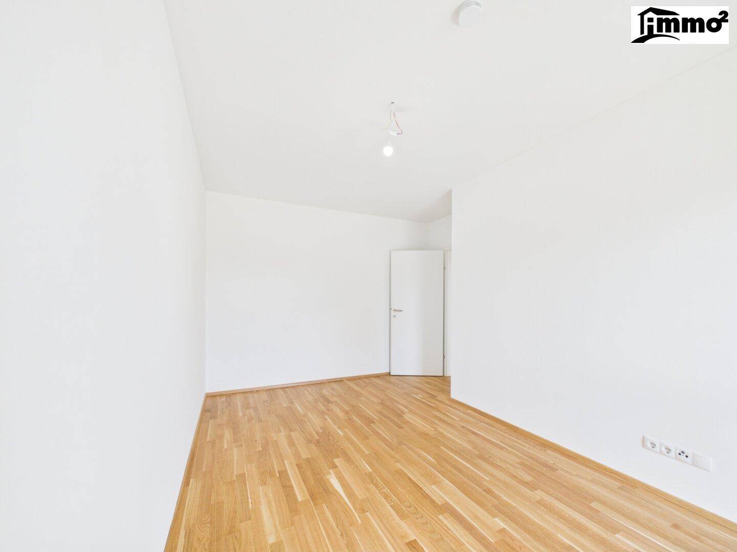 Heller, leerer Raum mit Holzboden und einer Tür, ideal für verschiedene Nutzungsmöglichkeiten.