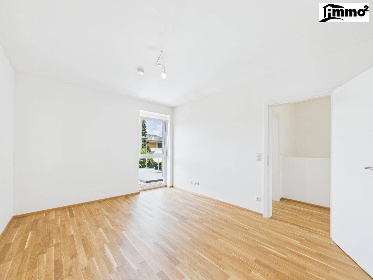 Helles, leeres Zimmer mit Parkettboden und weiß gestrichenen Wänden, bereit zur individuellen Gestaltung.