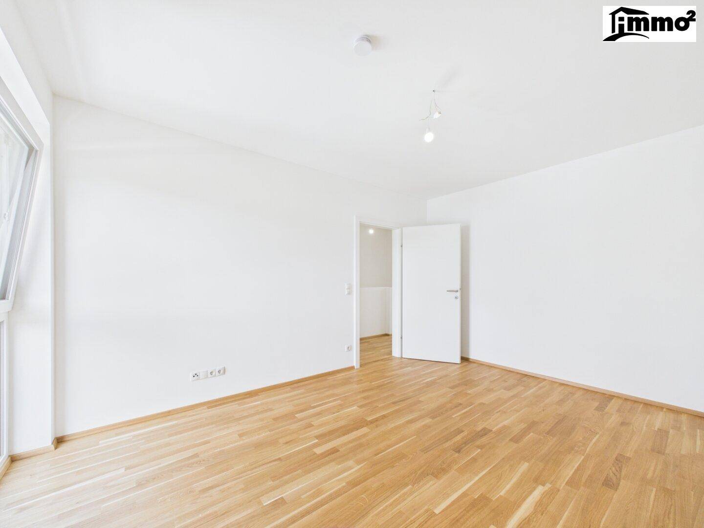 Geräumiges, helles Zimmer mit Holzboden und weißer Einrichtung, ideal für verschiedene Nutzungsmöglichkeiten.