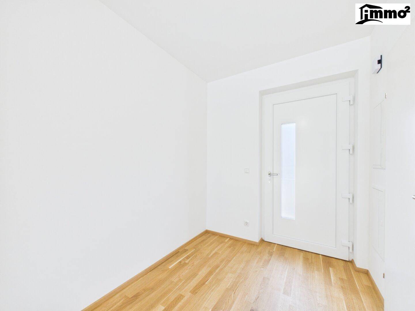 Heller Raum mit Holzboden und einer modernen Tür mit Glaseinsatz, vielseitig nutzbar.