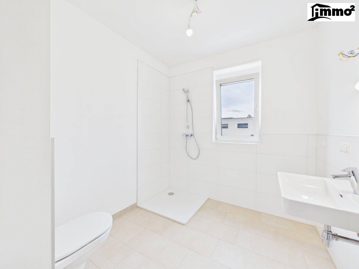 Modernes Badezimmer in Weiß mit ebenerdiger Dusche, Toilette und Fenster für Tageslicht.
