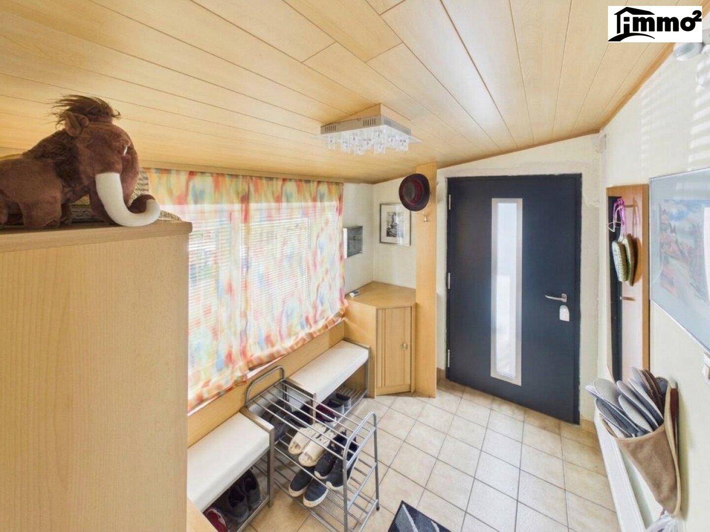 Eingangsbereich mit Fliesenboden, Holzdecke und praktischer Schuhablage sowie Sitzgelegenheit.