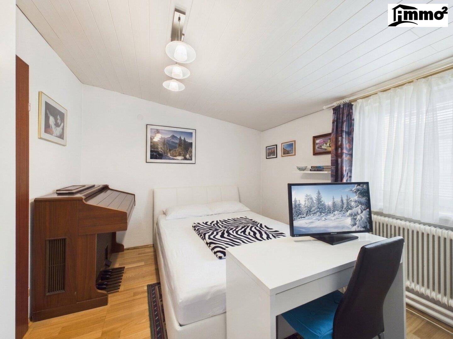 Schlafzimmer mit Einzelbett, Schreibtisch und einem Klavier, ideal als Gäste- oder Arbeitszimmer.