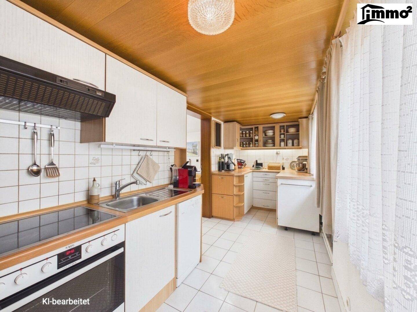 Funktionale Küche mit weißen Schränken, Holztheke, Herd und Spüle, unter einer Holzdecke.