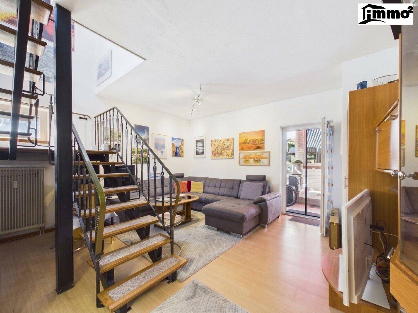 Geräumiges Wohnzimmer mit Wendeltreppe, bequemer Couch und Zugang zu einem Außenbereich.