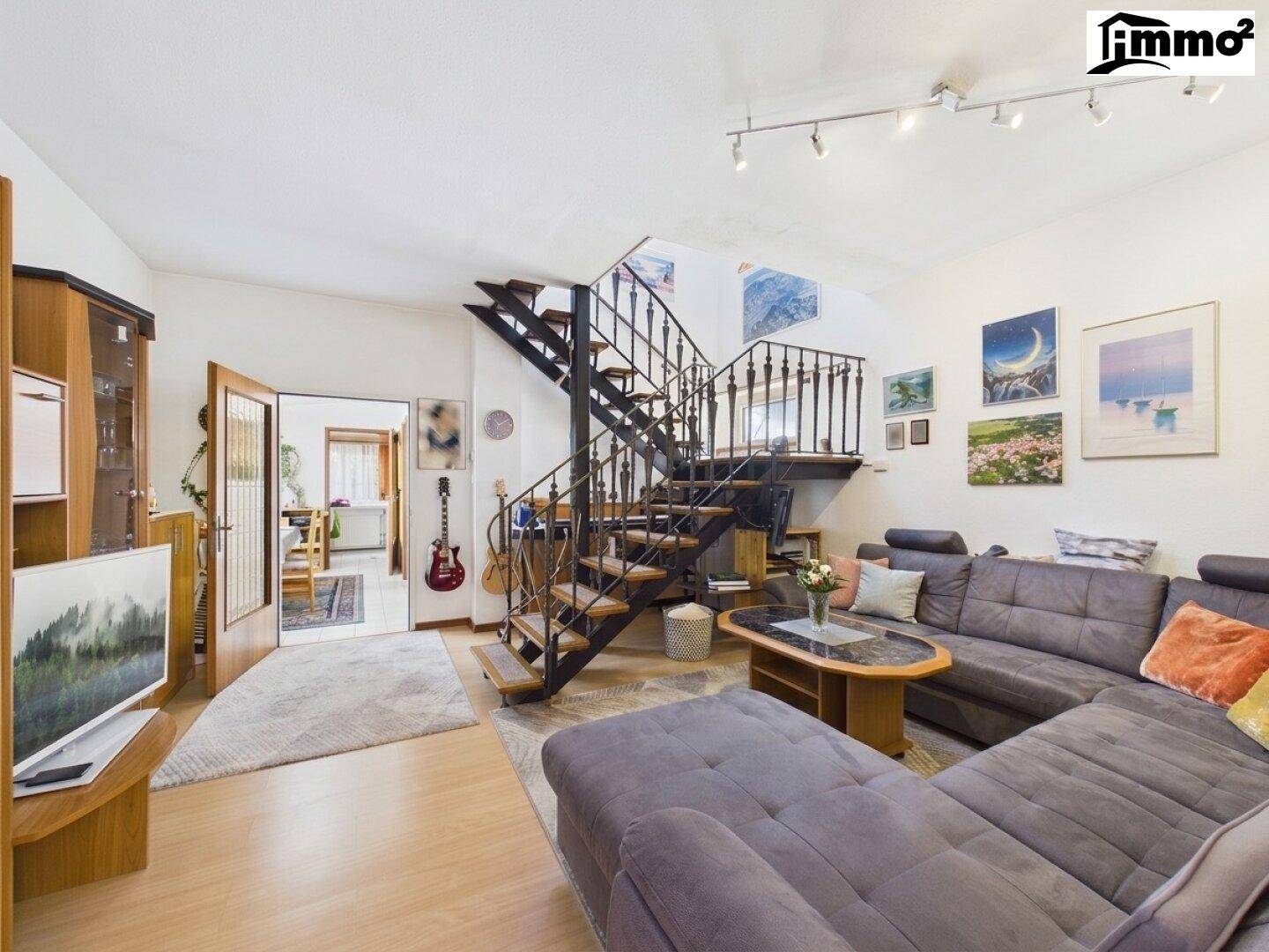 Gemütliches Wohnzimmer mit großer Couch, Holzfußboden und einer eleganten Wendeltreppe.