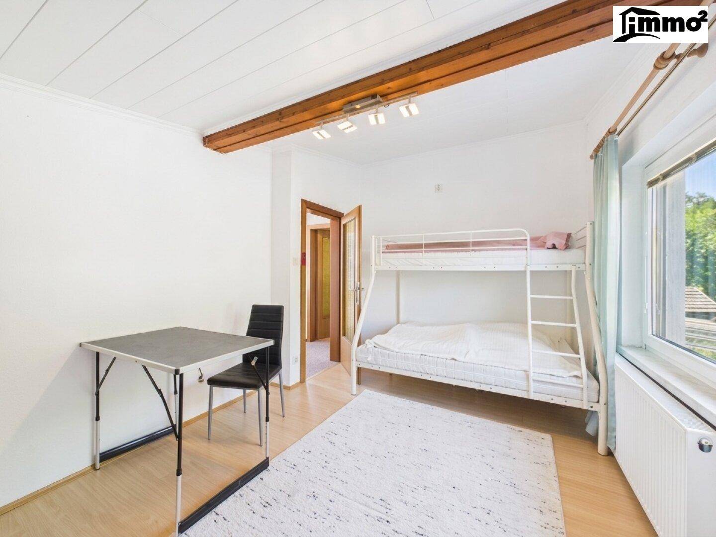 Kinderzimmer oder Gästezimmer mit Etagenbett, Schreibtisch und hellem Holzfußboden.
