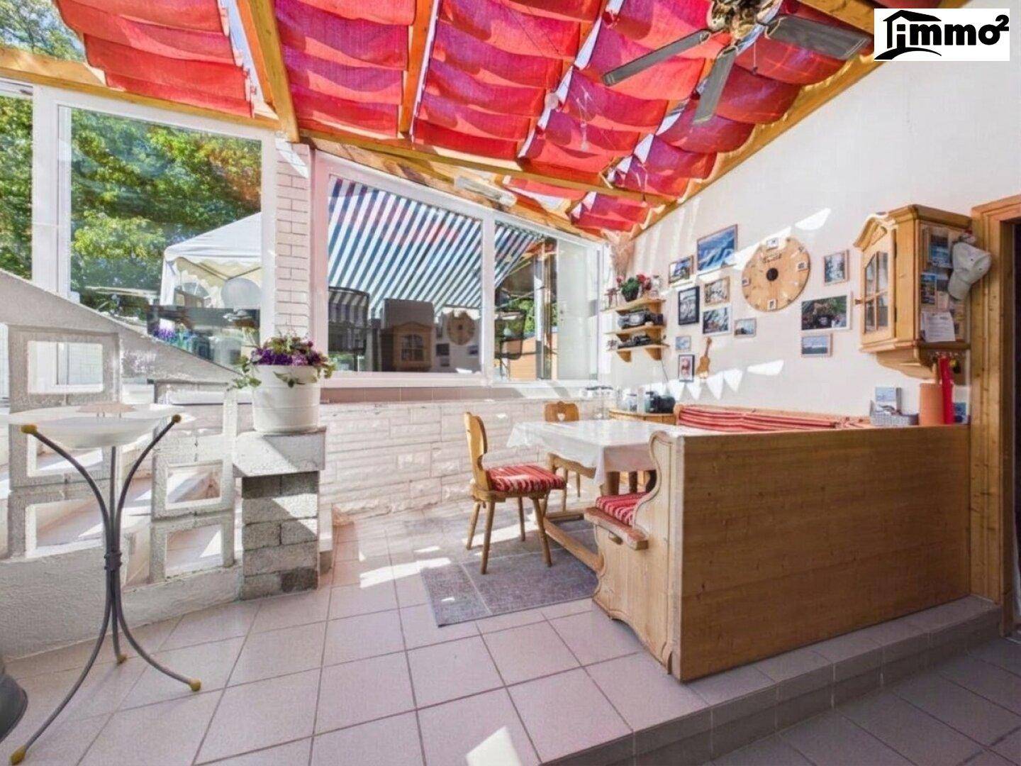 Gemütlicher Wintergarten mit Fliesenboden, Essbereich und einer dekorativen roten Stoffdecke.