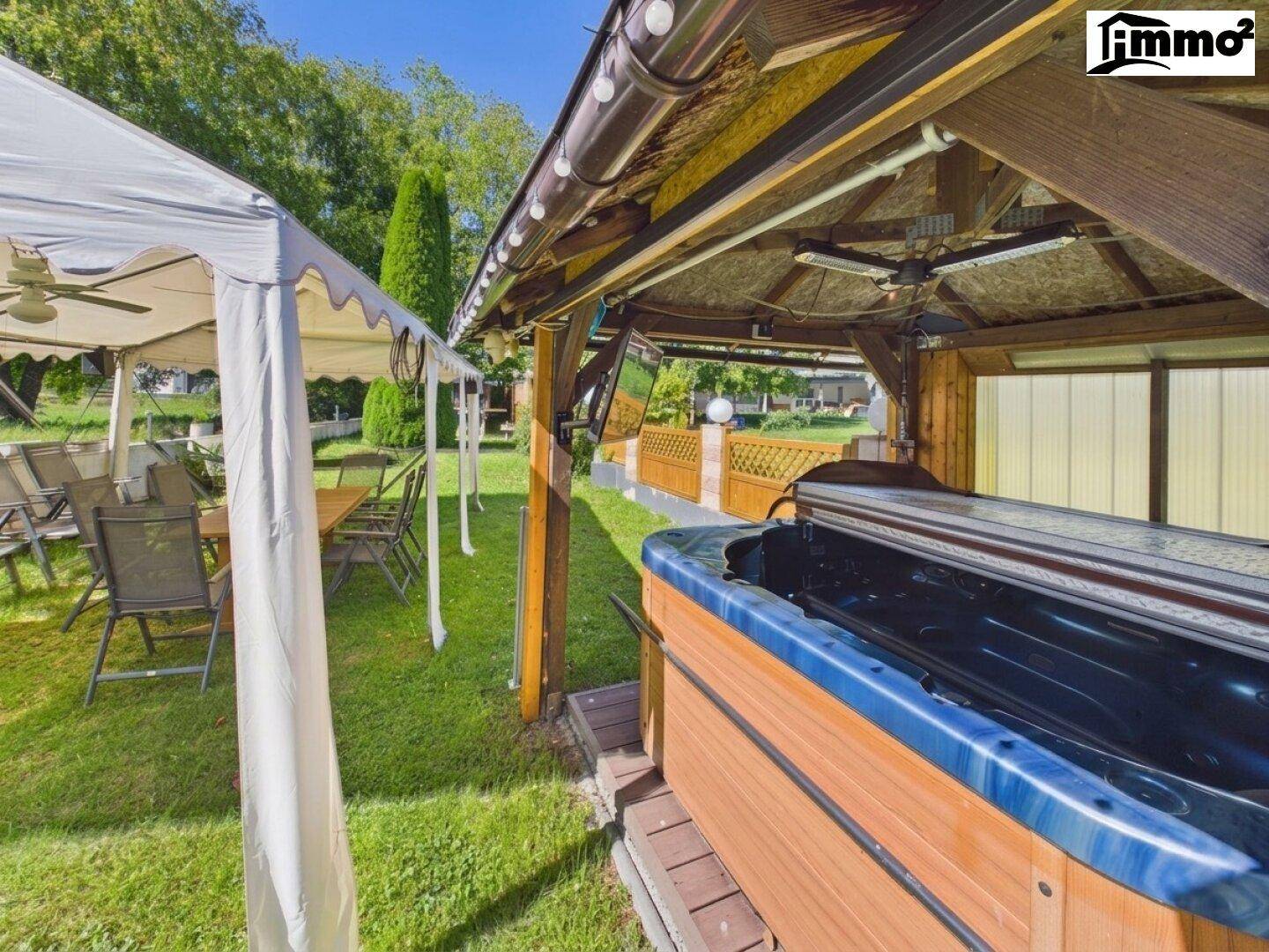 Großer Gartenbereich mit Whirlpool unter einem Pavillon und einem weiteren Essbereich im Freien.