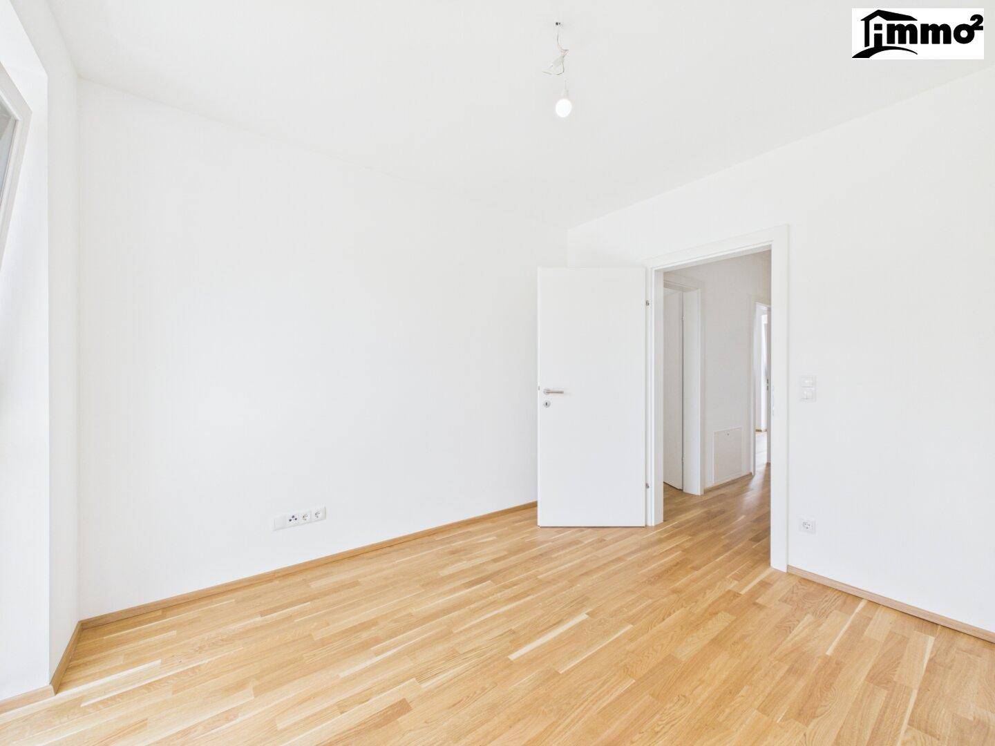 Helles, leeres Zimmer mit Parkettboden und weißen Wänden, bereit zur individuellen Gestaltung.