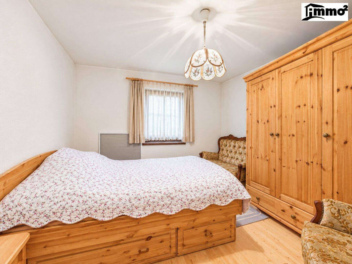 Schlafzimmer im Landhausstil mit Holzbett, großem Kleiderschrank und traditioneller Einrichtung.