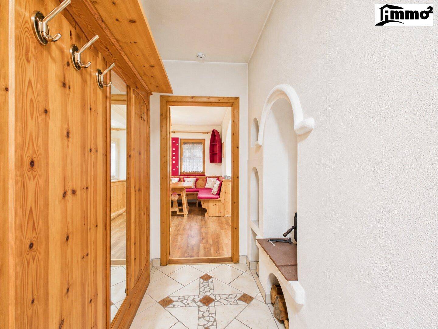 Heller Flur mit Holzwandgarderobe und traditionellen Fliesen, der zum Essbereich führt.