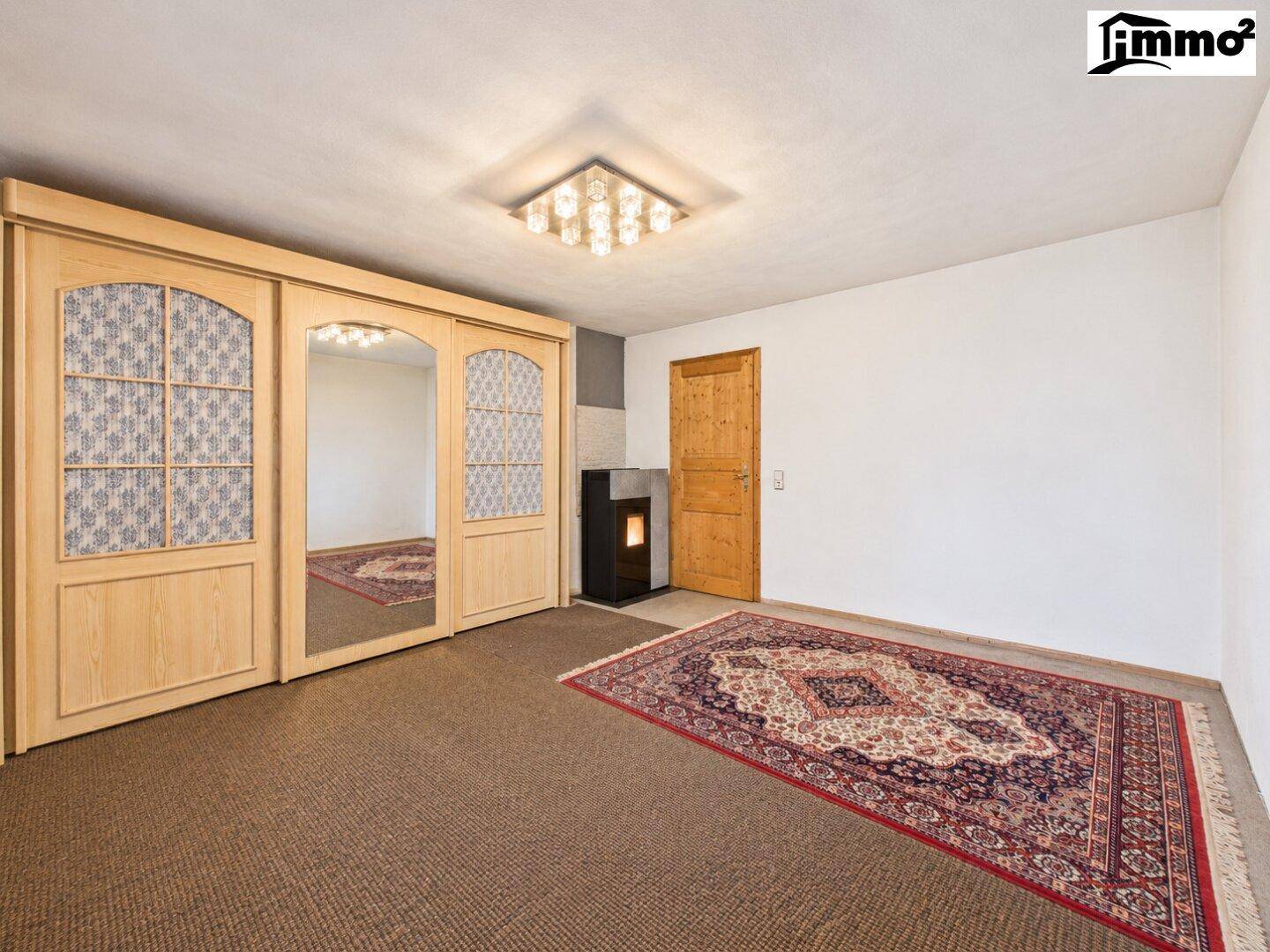 Geräumiges Zimmer mit Schiebetürenschrank, Teppichboden und modernem Ofen.