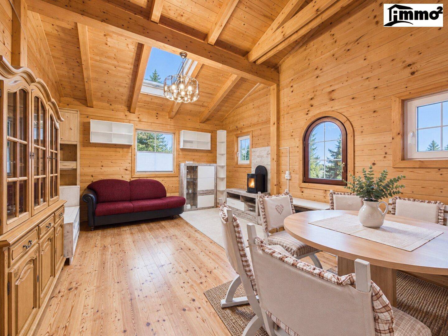 Offener Wohn- und Essbereich im Chalet-Stil mit Holzwänden, Kamin und Dachfenster.