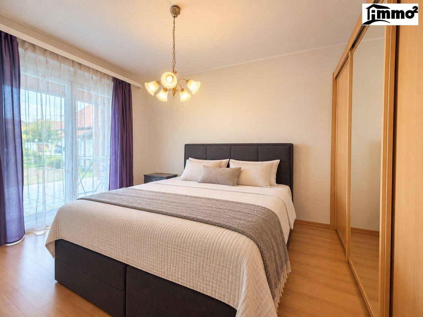 Schlafzimmer mit Doppelbett, großem Spiegelschrank und Zugang zur Terrasse.