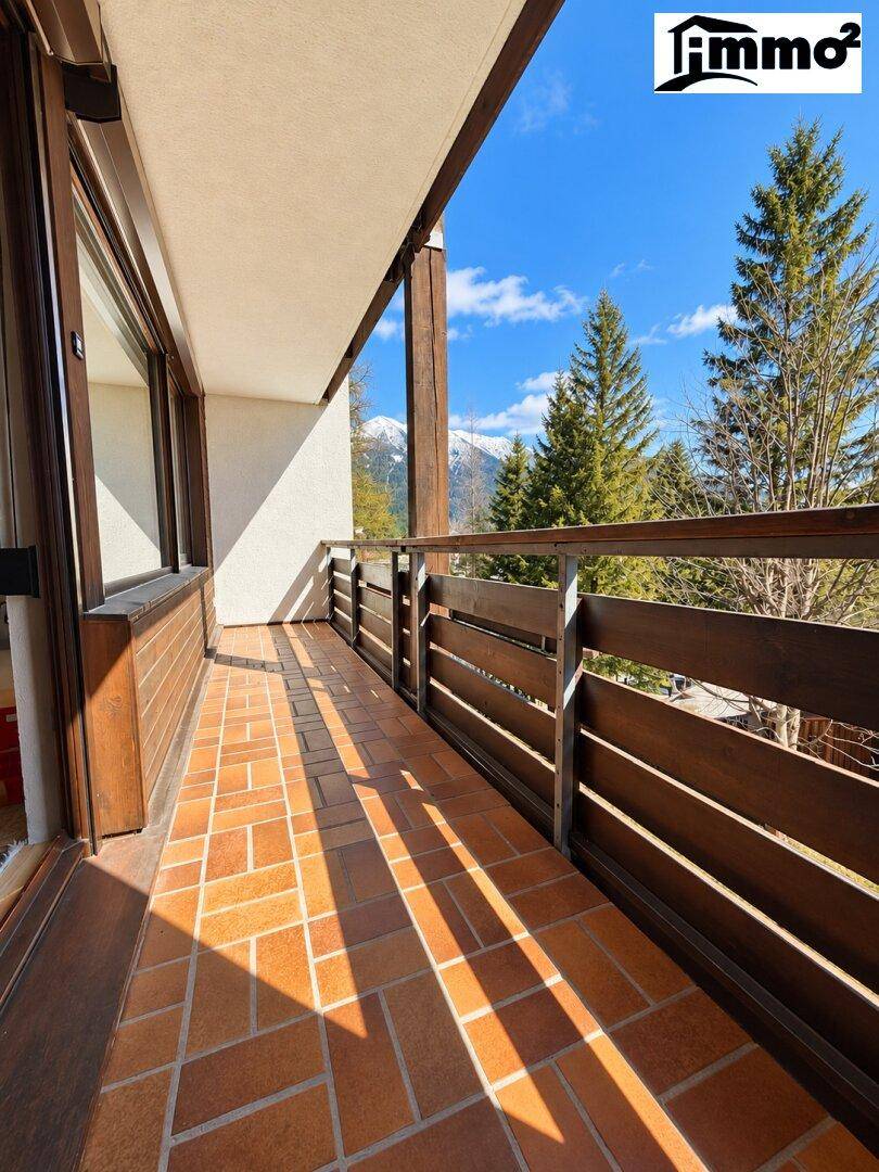 Sonniger Balkon mit Terrakotta-Fliesen und Holzbalken, bietet Blick auf die Berge.