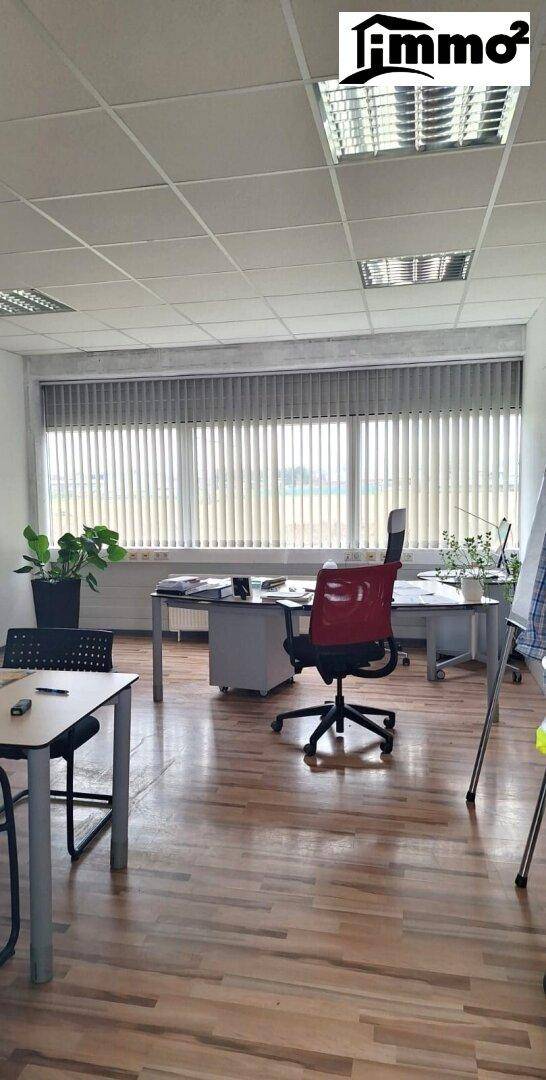Helles Büro mit Holzfußboden, vertikalen Jalousien und Blick auf die weite Landschaft.