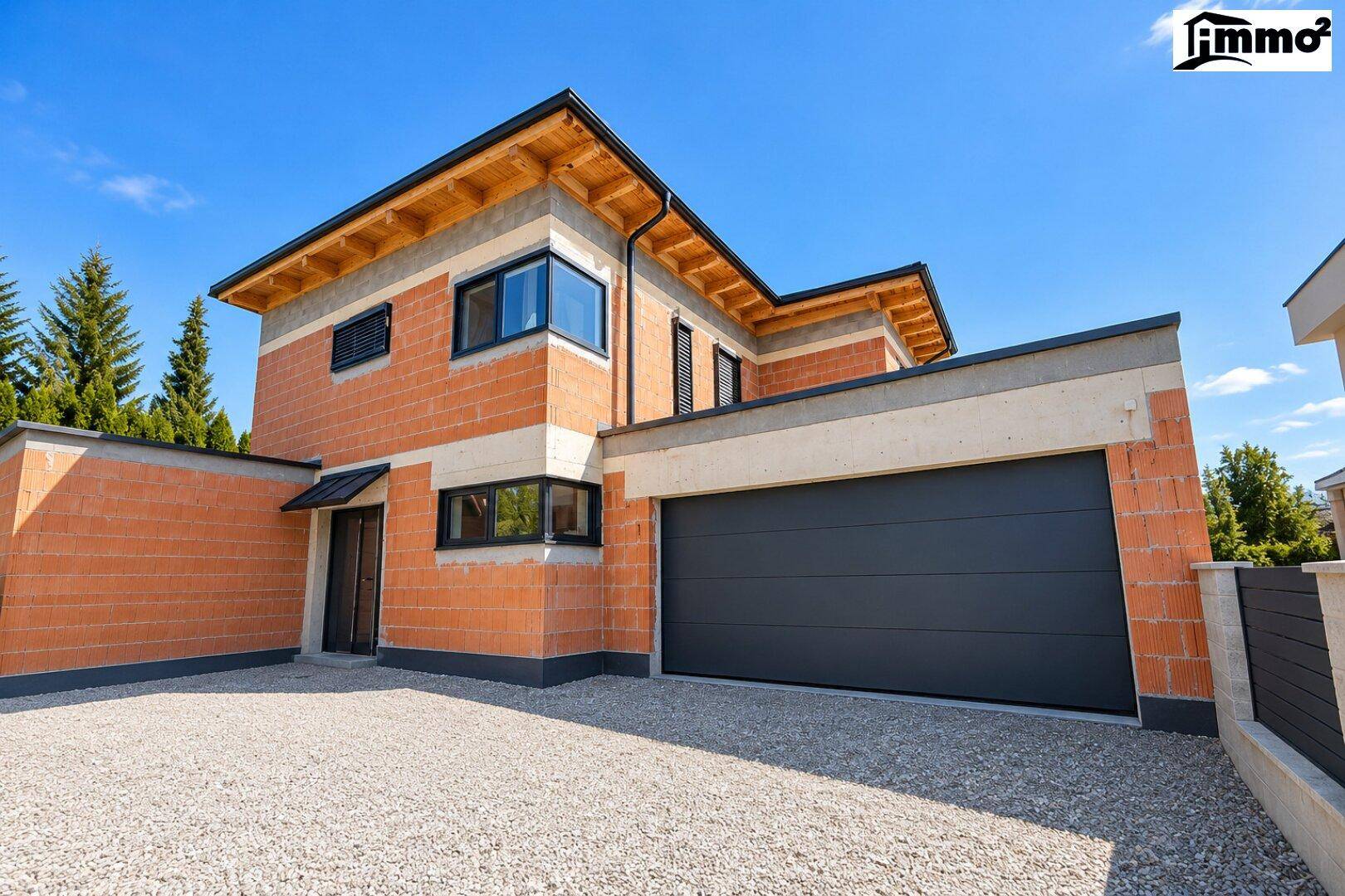 Neubau-Einfamilienhaus mit moderner Architektur, Garage und Kiesauffahrt.