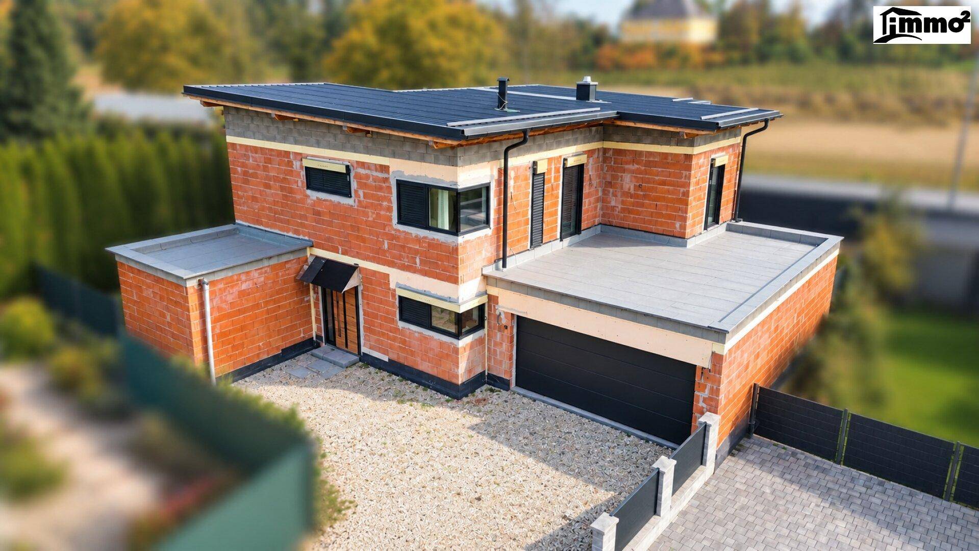 Luftaufnahme eines modernen Neubaus mit Flachdach und Garage in ländlicher Umgebung.