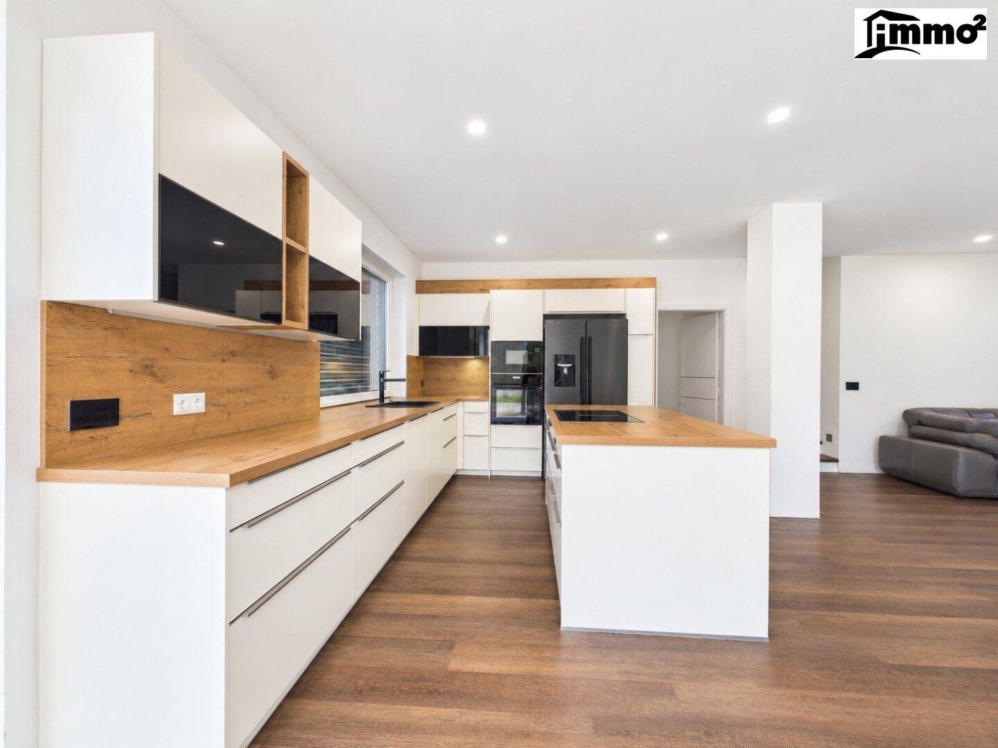 Moderne Einbauküche mit weiß-holzfarbenen Fronten, Kochinsel und integrierten Geräten.