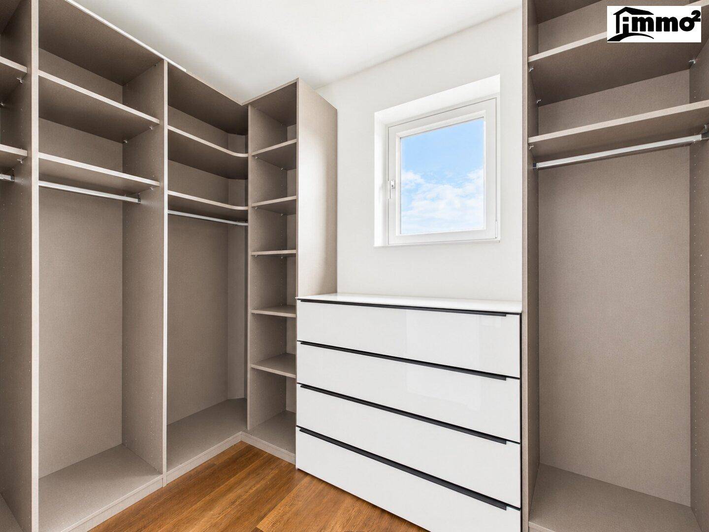Begehbarer Kleiderschrank mit integrierten Regalen, Schubladen und einem Fenster für Tageslicht.