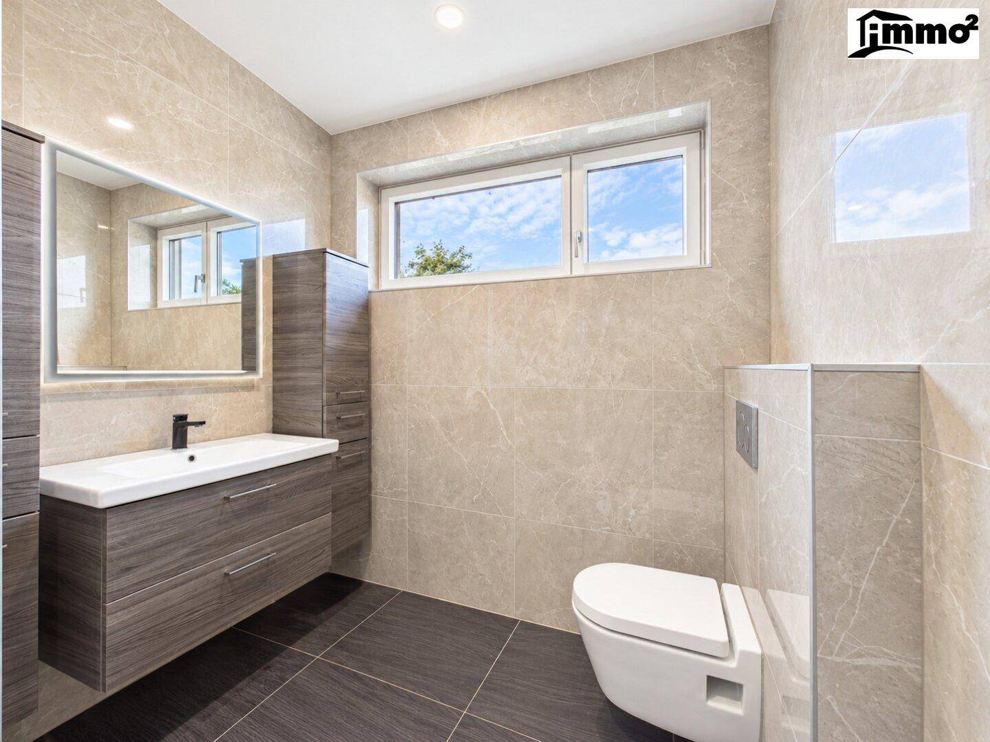 Elegantes Badezimmer mit beigefarbenen Fliesen, wandhängendem WC und modernem Waschtisch.