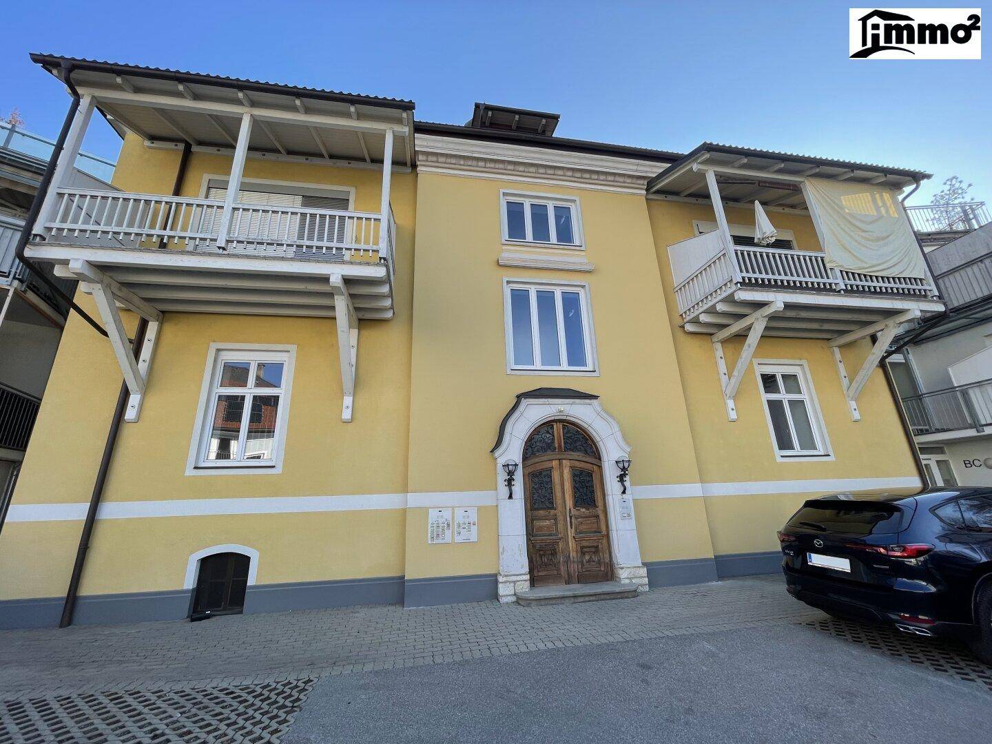 Historisches gelbes Gebäude mit mehreren Balkonen und einer verzierten Eingangstür.
