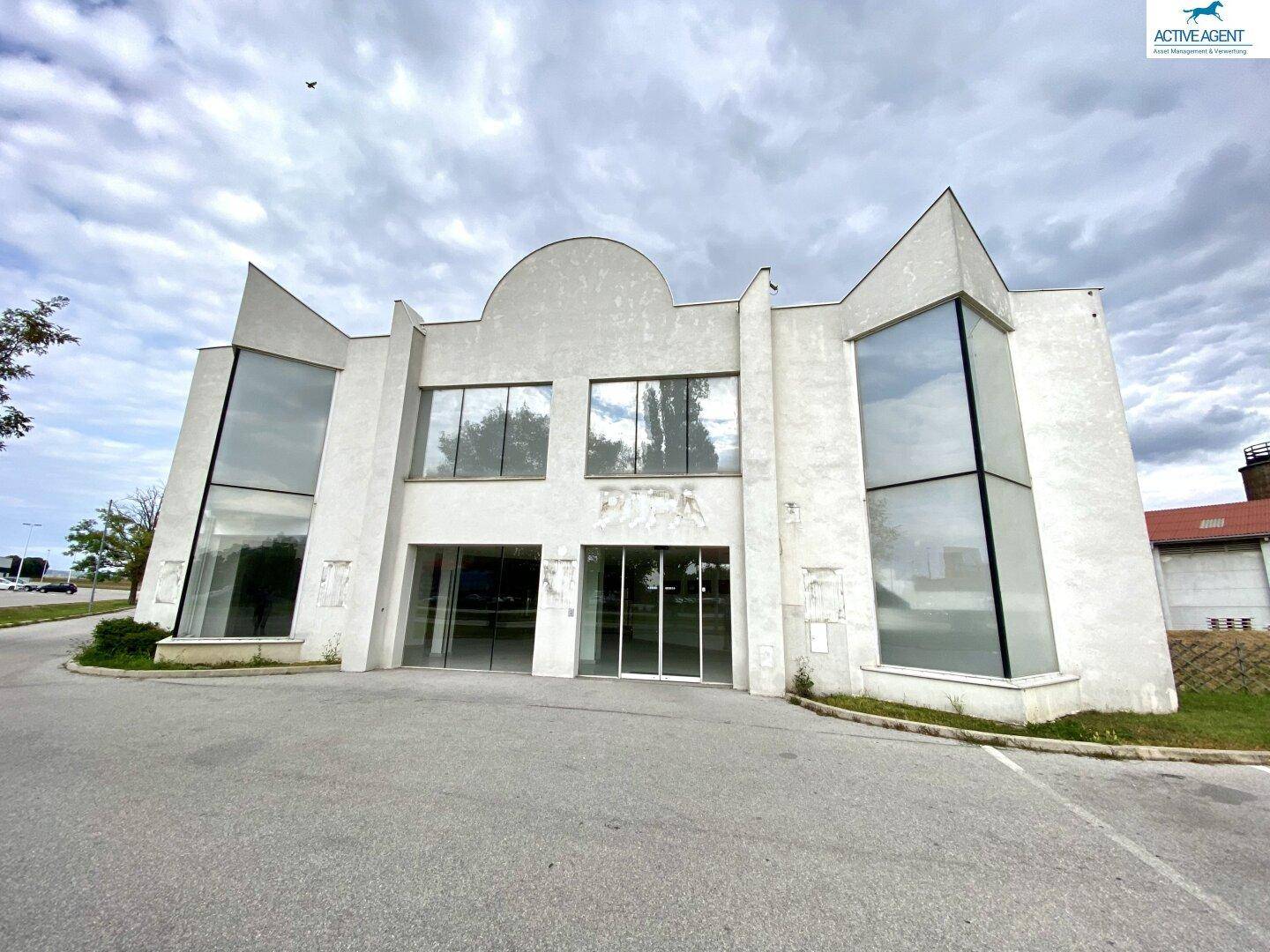 Leeres Geschäftsgebäude mit großen Glasflächen und dekorativen Elementen an der Fassade.