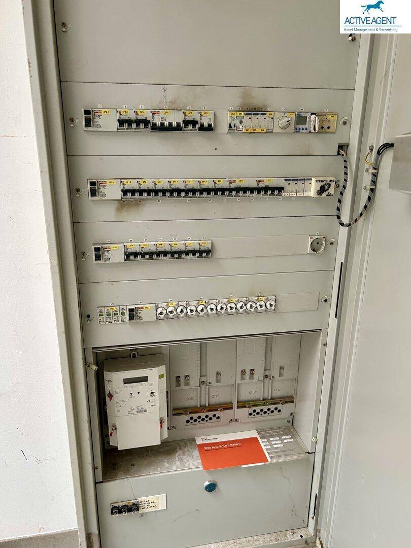 Elektrischer Verteilerkasten mit zahlreichen Sicherungen und Zählern, der die Stromversorgung des Gebäudes regelt.