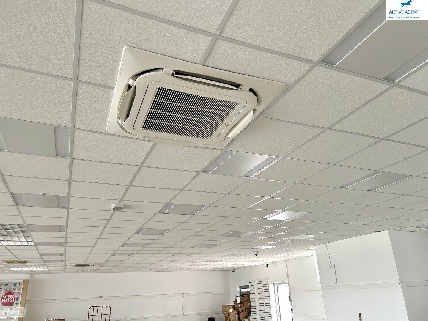 Nahaufnahme einer abgehängten Decke mit integrierten Beleuchtungselementen und einer Klimaanlage.