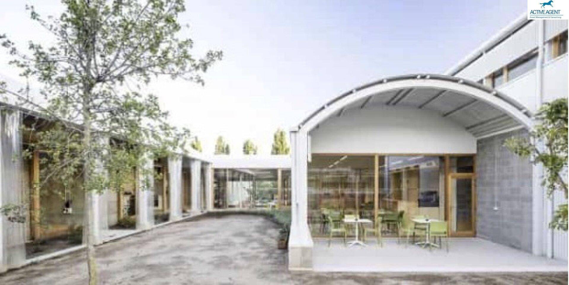 Außenbereich eines modernen Gebäudes mit überdachter Terrasse und Sitzgelegenheiten.