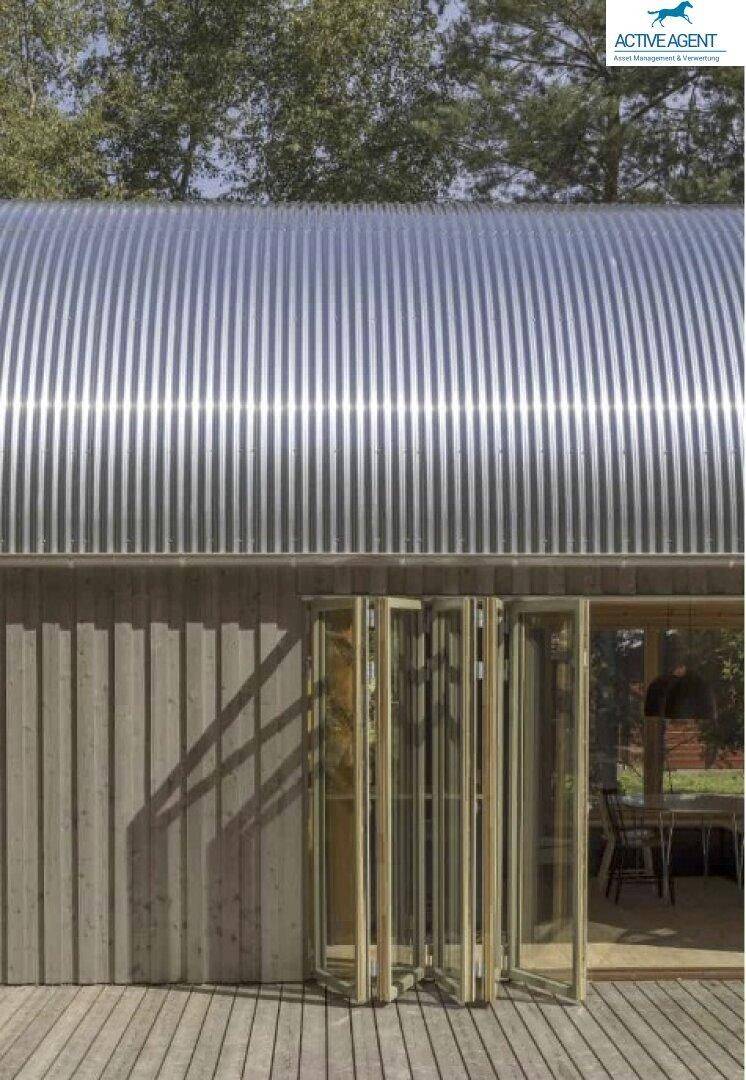Detailansicht einer modernen Gebäudefassade mit Falttüren und gewelltem Metalldach.