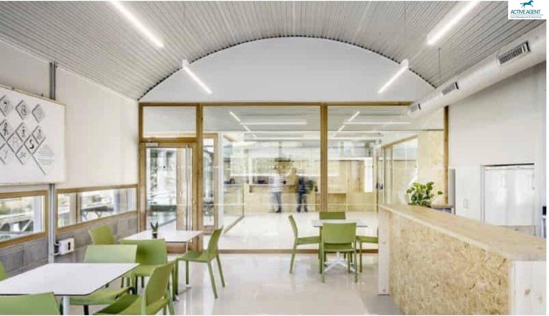 Heller Cafébereich mit modernen Möbeln, großen Fenstern und gewölbter Decke.