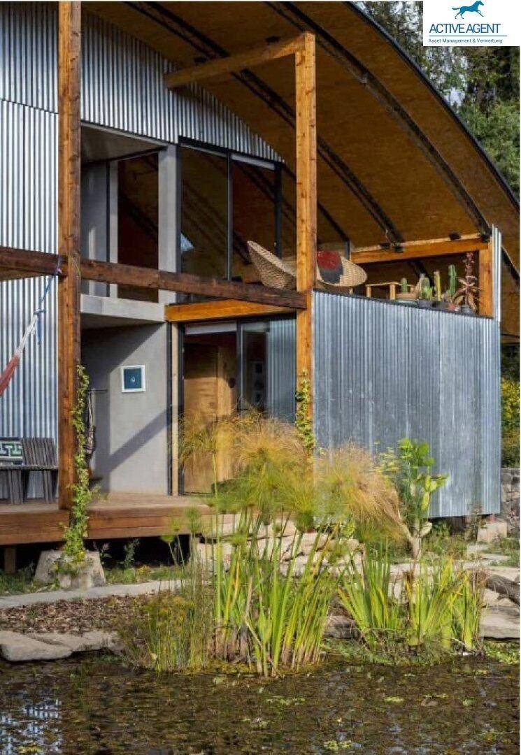 Außenansicht eines modernen Gebäudes mit Holz- und Metallfassade am Wasser.