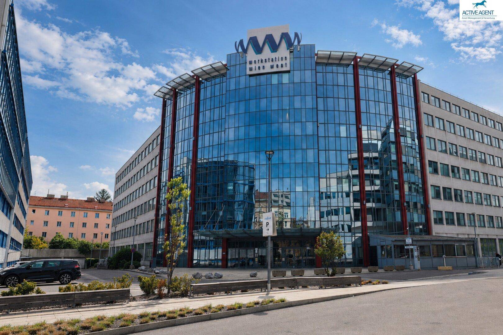 Beeindruckendes Bürogebäude mit geschwungener Glasfassade und markantem Eingangsbereich unter einem bewölkten Himmel.