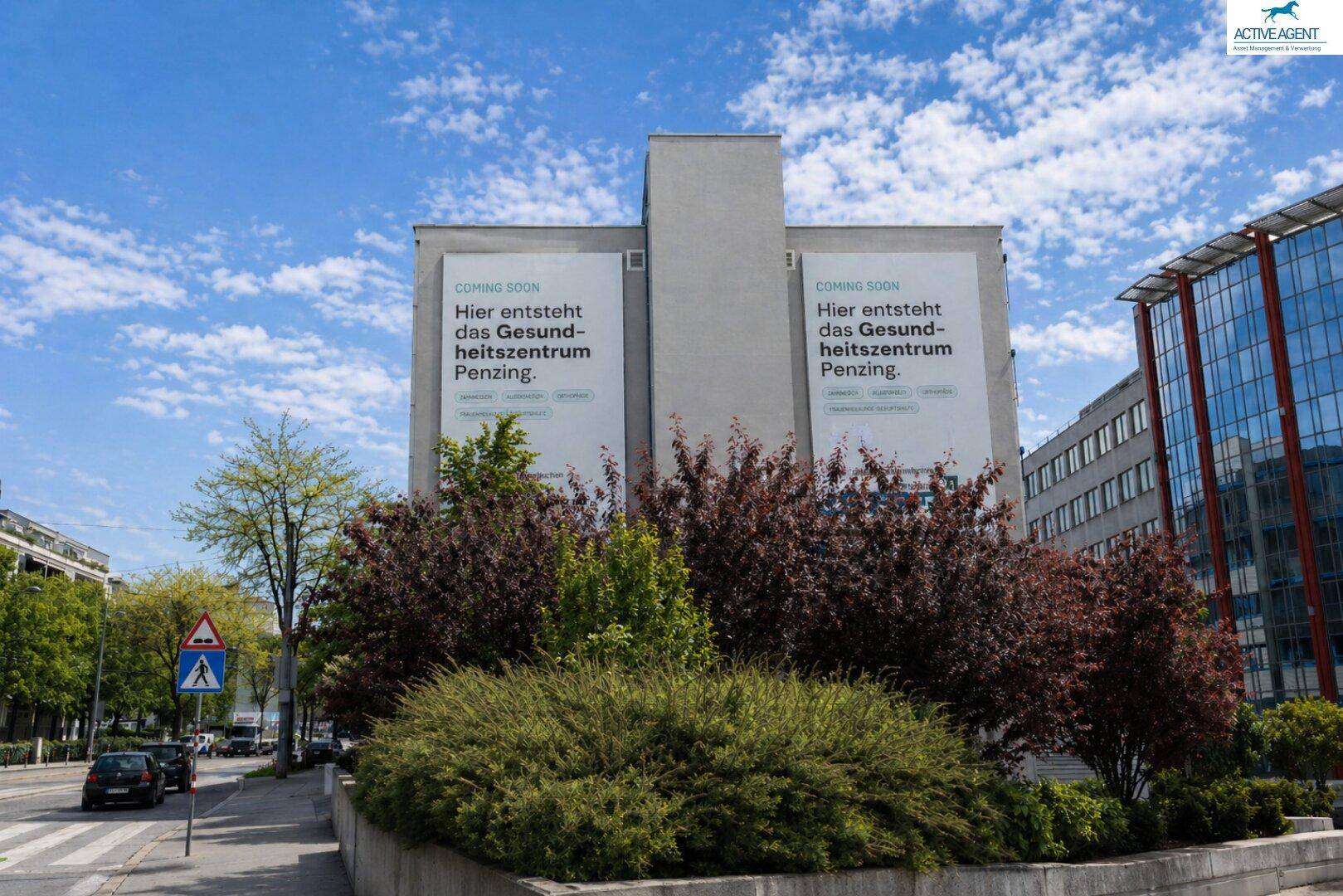 Seitenansicht eines modernen Gebäudes mit großen Werbebannern für ein Gesundheitszentrum, umgeben von üppigem Grün.