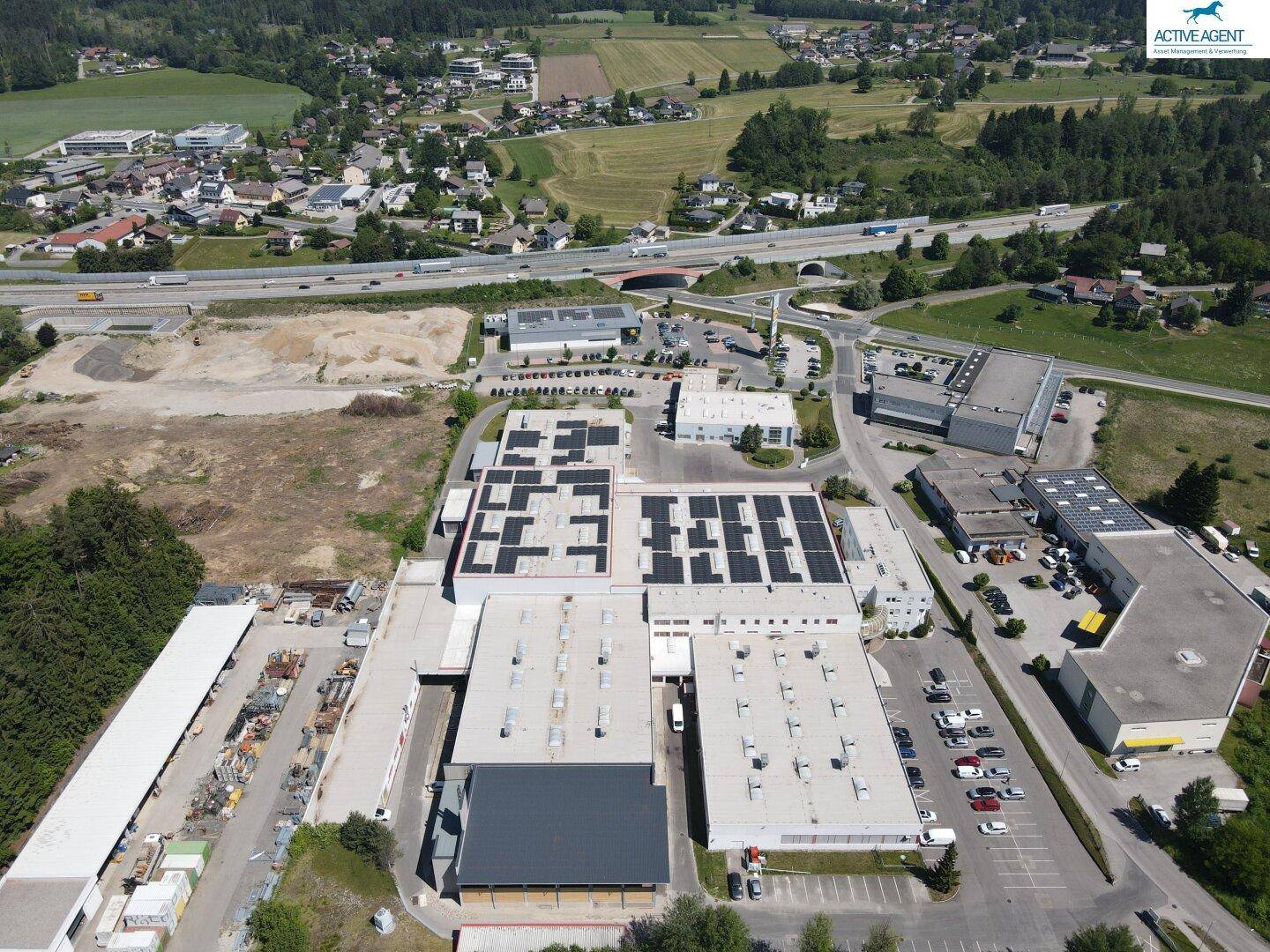 Panoramische Luftaufnahme eines Gewerbeparks mit Photovoltaikdächern und guter Anbindung an die Infrastruktur.