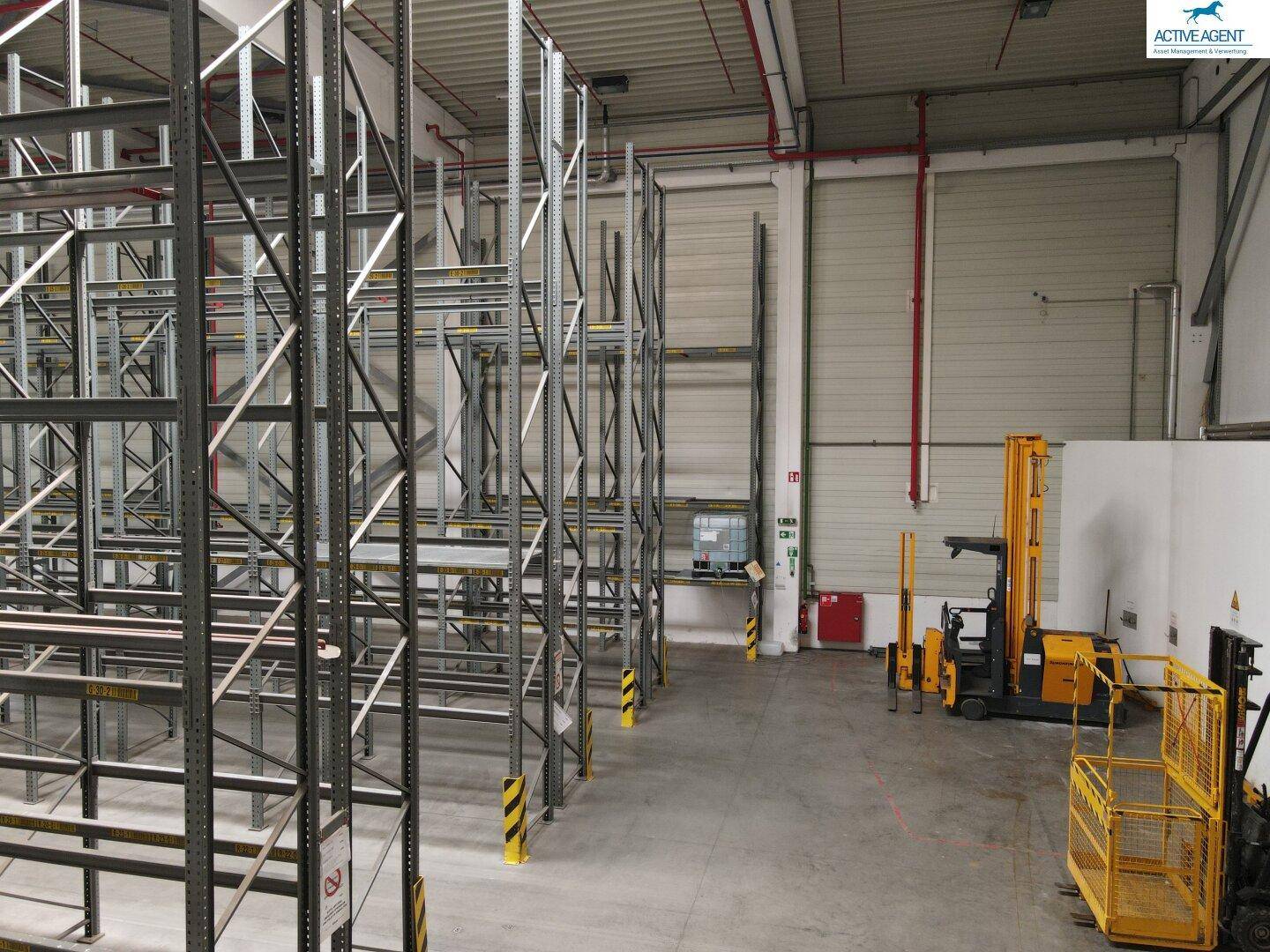 Lagerhalle mit hohen Regalsystemen, einem Gabelstapler und einem Industrieboden aus Beton.