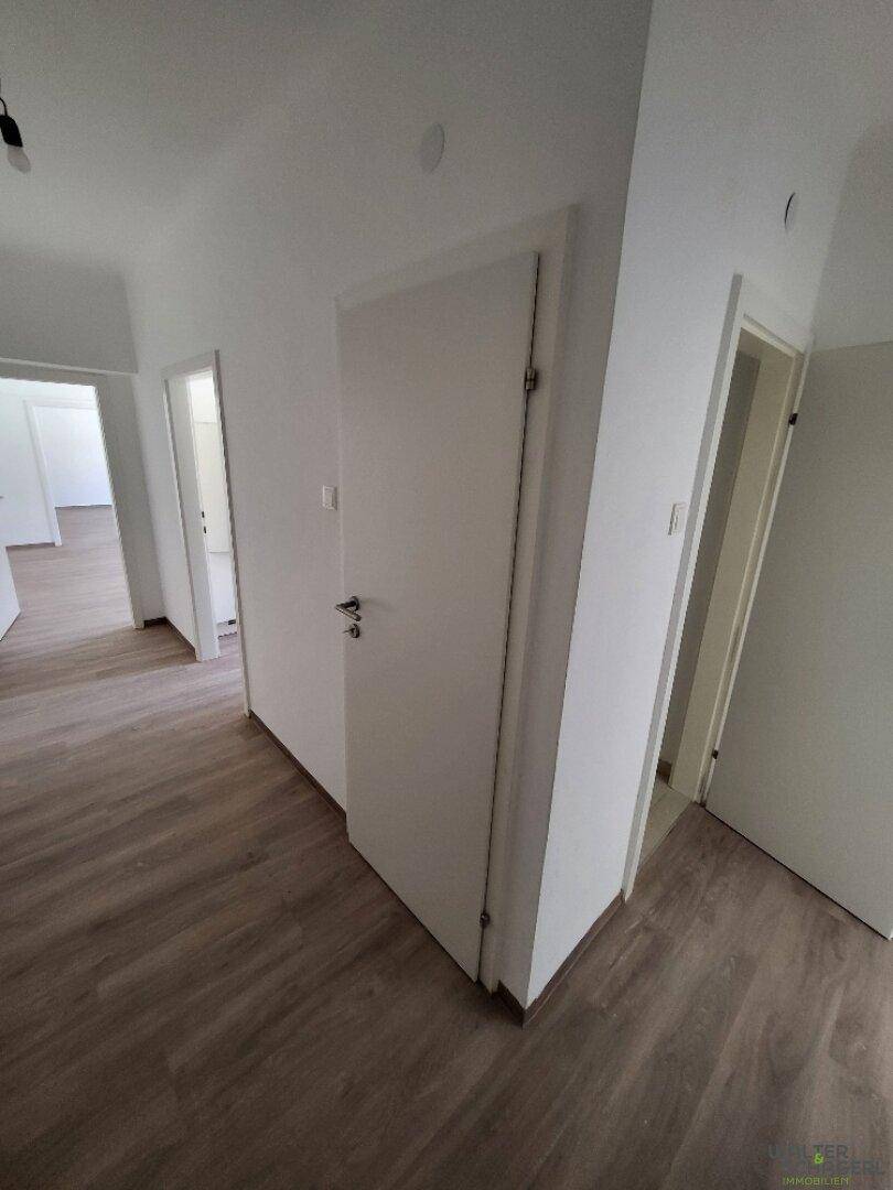 Langer, heller Flur mit Laminatboden und mehreren Türen, die zu den Wohnräumen führen.