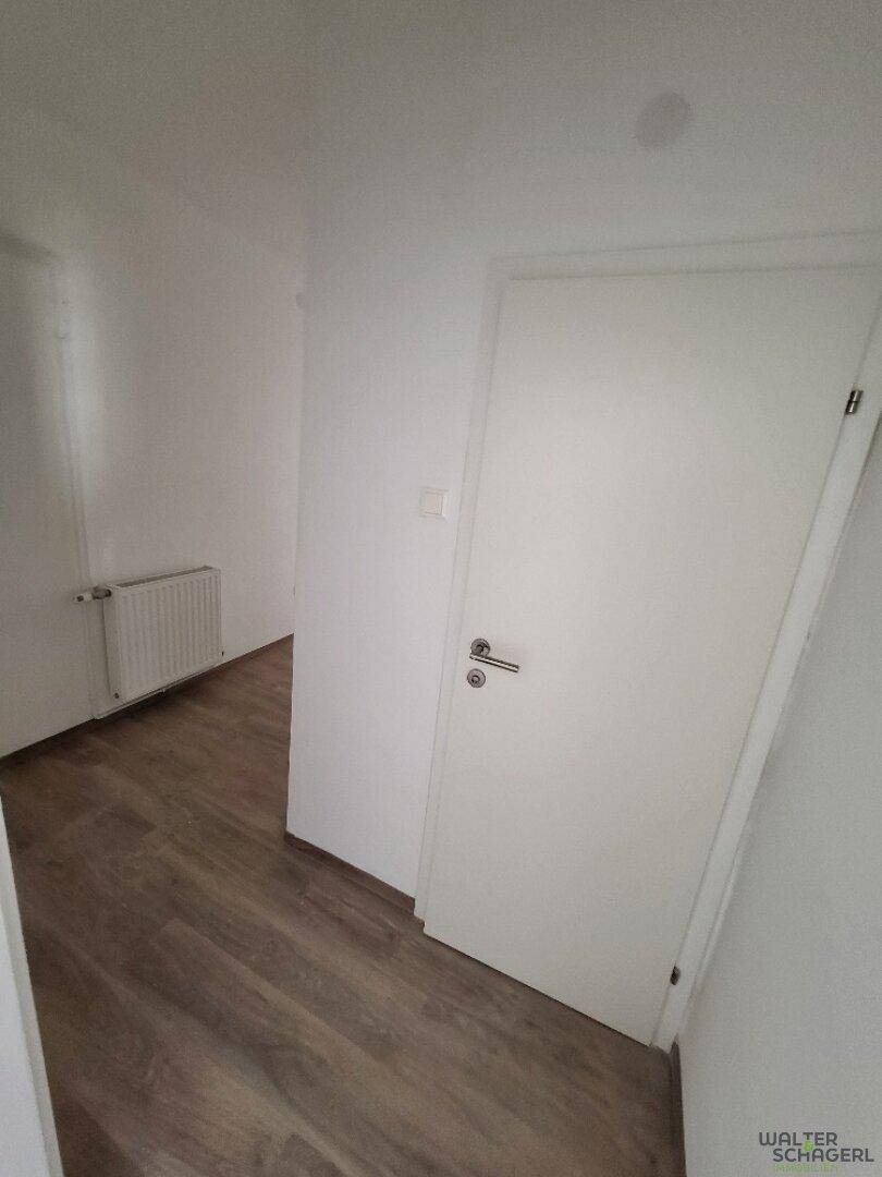 Schmaler Flur mit Laminatboden und weißer Tür, der die verschiedenen Bereiche der Wohnung verbindet.